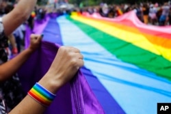 FILE - Revelers at the annual gay pride parade hold up a giant rainbow flag in Sao Paulo, Brazil, June 3, 2018. Rainbow flags will be allowed in stadiums at the 2022 World Cup as Qatar, with a strictly conservative religious code and anti-LGBTQ laws, says it accepts complying with FIFA regulations promoting tolerance and inclusion at matches.