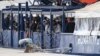 Migrants stand on the deck of the Humanity 1 rescue ship run by the German organization SOS Humanitarian at harbor in the port of Catania, Sicily, southern Italy, Nov. 6, 2022. 