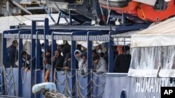Para migran berdiri di dek kapal penyelamat Humanity 1 yang dijalankan oleh organisasi Jerman SOS Humanitarian, di pelabuhan di Pelabuhan Catania, Sisilia, Italia selatan, Minggu, 6 November 2022. (Foto: AP)