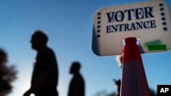 Voters pass a sign outside a polling site in Warwick, R.I., Nov. 7, 2022, after casting their ballots on the last day of early voting before the midterm election.