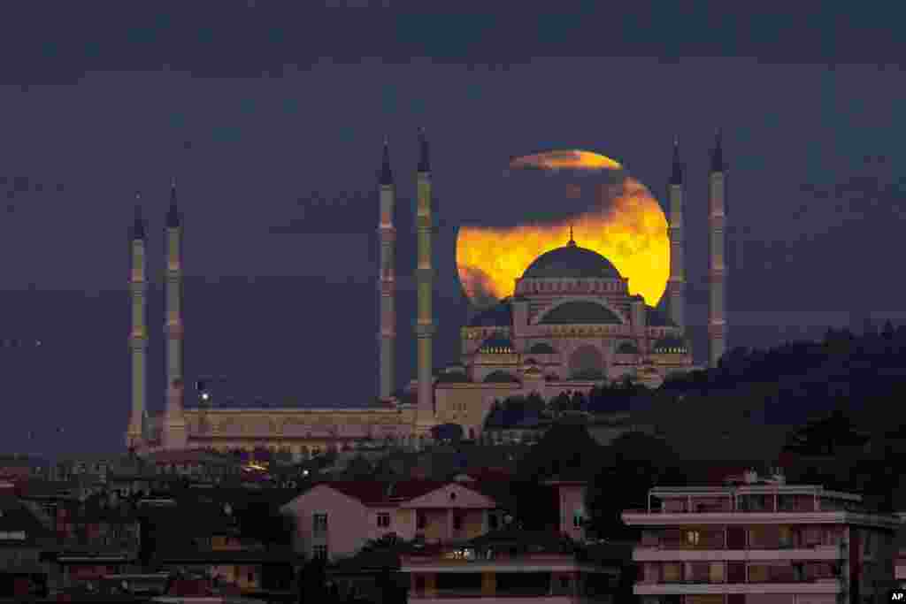 A full moon rises behind the Camlica mosque in Istanbul, Turkey.
