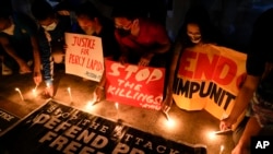 FILE - Activists light candles as they condemn the killing of Filipino journalist Percival Mabasa during a rally in Quezon city, Oct. 4, 2022. Authorities filed murder complaints against a top prison official and an aide they accused of masterminding the killing. 