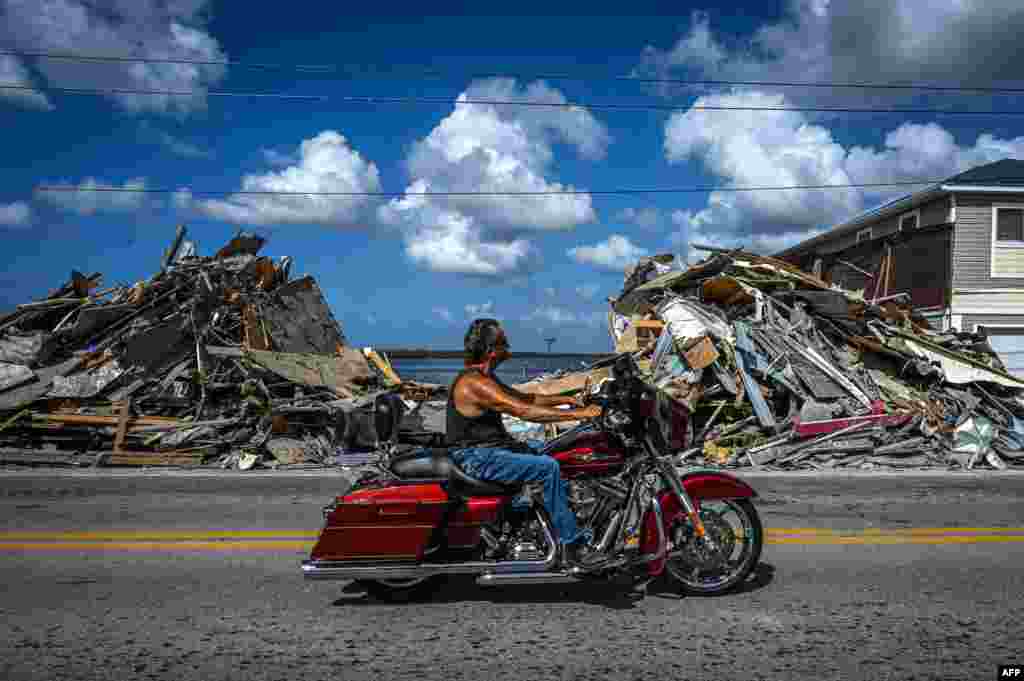 A motorcyclist rides past remains from a destroyed home after the passage of Hurricane Ian on Matlacha Island in Lee County, Florida, Nov. 7, 2022.