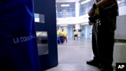 FILE - An officer stands guard as inmates eat at the Twin Towers Correctional Facility in Los Angeles, California, April 27, 2017.