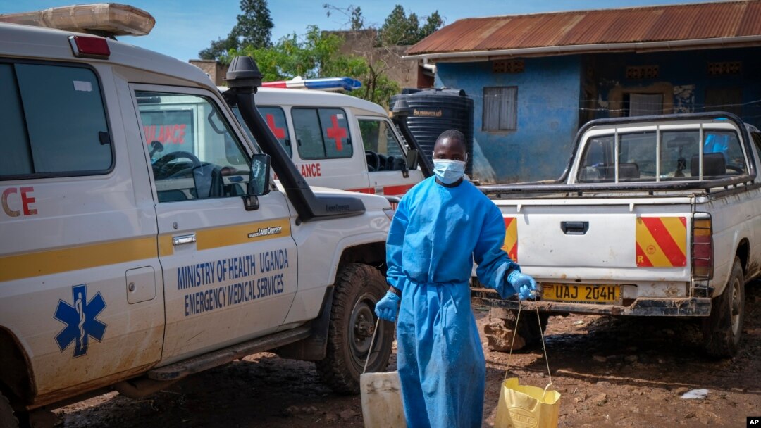 A man wearing protective clothing carries water to wash the interior of an ambulance used to transport suspected Ebola patients, in the town of Kassanda, Uganda, Nov. 1, 2022.
