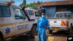 A man wearing protective clothing carries water to wash the interior of an ambulance used to transport suspected Ebola patients, in the town of Kassanda, Uganda, Nov. 1, 2022.
