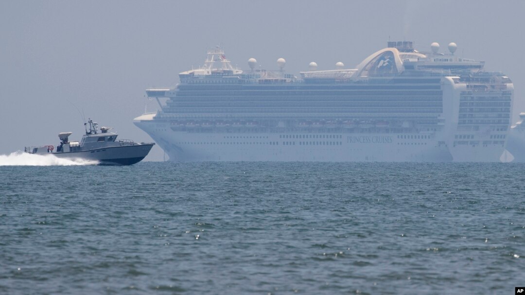 Sebuah kapal milik militer Filipina melintas di depan kapal pesiar milik Ruby Princess yang berlabuh di Teluk Filipina untuk penyelidikan wabah Covid-19, 7 Mei 2020. (Foto: AP)
