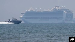 Sebuah kapal milik militer Filipina melintas di depan kapal pesiar milik Ruby Princess yang berlabuh di Teluk Filipina untuk penyelidikan wabah Covid-19, 7 Mei 2020. (Foto: AP)