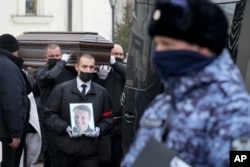 FILE —Workers carry the coffin and a portrait of Russian opposition leader Alexei Navalny out of the Church of the Icon of the Mother of God Soothe My Sorrows, in Moscow, Russia, March 1, 2024.