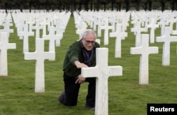 Jeffrey Gusky, a U.S. explorer and WWI enthusiast, touches the tombstone of fallen U.S. soldier Burton Holmes of the First World War’s 371st infantry regiment, an African American unit, at the Meuse-Argonne American Cemetery and Memorial.