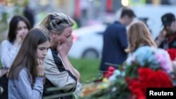 Seorang perempuan menangis di dekat tugu peringatan yang didirikan sementara, untuk menghormati para korban penembakan di Sekolah Nomor 175 di Kazan, Rusia, 11 Mei 2021. (REUTERS / Artem Dergunov)

