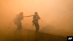 Firefighters battle a fire along the Ronald Reagan (118) Freeway in Simi Valley, California, Nov. 12, 2018.