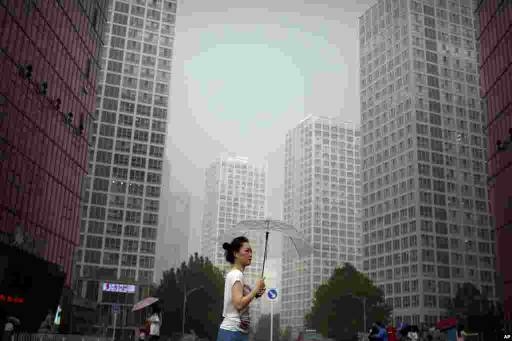 A woman carries an umbrella as she walks through the central business district of Beijing during a rain shower.