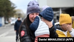 A Ukrainian refugee holding her child cries after she arrived at the Siret border crossing between Romania and Ukraine on April 18, 2022. (Daniel MIHAILESCU / AFP)