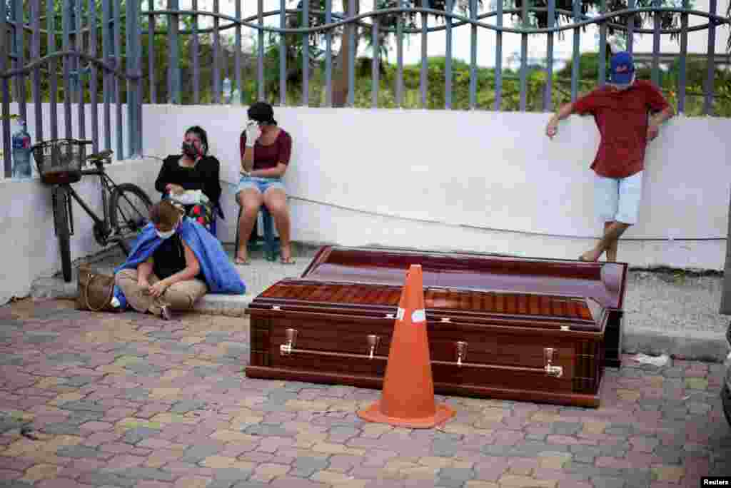 Personas esperan junto a los ataúdes fuera del Hospital General Guasmo Sur para recoger los cuerpos de sus familiares.&nbsp;