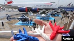 An Airbus employee presents three model airplanes in blue, white and red, made from starch using a 3D printing technique during the opening of 50th Paris Air Show, at the Le Bourget airport near Paris, June 17, 2013. In the future the company hopes to use