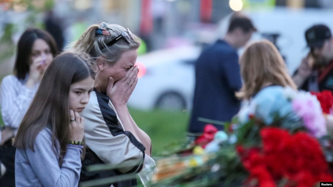 Seorang perempuan menangis di dekat tugu peringatan yang didirikan sementara, untuk menghormati para korban penembakan di Sekolah Nomor 175 di Kazan, Rusia, 11 Mei 2021. (REUTERS / Artem Dergunov)
