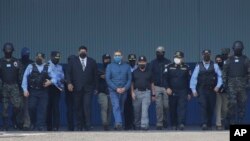 El expresidente de Honduras Juan Orlando Hernández, en el centro, con camisa azul y fuertemente escoltado por las fuerzas de seguridad, en el momento de su entrega a las autoridades estadounidenses en la base aérea de Tegucigalpa, el 21 de abril de 2022.