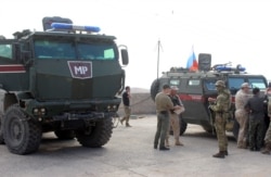 FILE - A handout picture obtained from the Syrian Kurdish North Press Agency on October 24, 2019 shows Russian military police troops standing next to their armored vehicles in the northeastern Syrian city of Kobane on Oct. 23, 2019.
