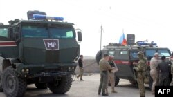 A handout picture obtained from the Syrian Kurdish North Press Agency on Oct. 24, 2019 shows Russian military police troops standing next to their armored vehicles in the northeastern Syrian city of Kobane on Oct. 23, 2019. 