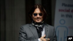 Aktor AS Johnny Depp memberi isyarat kepada penggemar dan media saat ia tiba di Pengadilan Tinggi di London, Kamis, 23 Juli 2020. (Foto: AP)