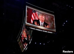 U.S. Republican Presidential Nominee Donald Trump is shown on video monitors as he speaks live to the crowd from New York at the Republican National Convention in Cleveland, Ohio, July 19, 2016.