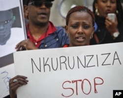 FILE - A demonstrator holds up a poster during a rally by Burundi nationals and supporters outside U.N. headquarters, protesting atrocities and human rights violations in Burundi under the government of President Pierre Nkurunziza, Apr. 26, 2016, in New York.
