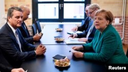 El jefe de la OMC, Roberto Azevedo y la canciller alemana, Angela Merkel, sostienen un encuentro al margen de una conferencia organizada por la Federación de Industrias Alemanas, en Berlin.
