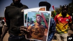 A man holds a portait of Lt. Col. Paul-Henri Damiba who has taken the reins in Burkina Faso, in Ouagadougou, Jan. 25, 2022.