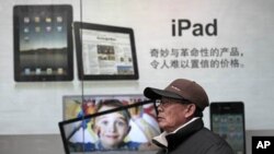 A man stands near Apple's iPad advertisement in Shanghai, China, Jan. 26, 2011