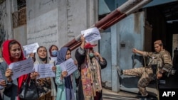 Seorang anggota Taliban menyaksikan perempuan Afghanistan selama demonstrasi menuntut hak yang lebih baik bagi perempuan di depan bekas Kementerian Urusan Perempuan di Kabul pada 19 September 2021. (Foto: AFP/Blent Kilic)