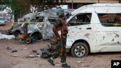 A soldier walks past damaged buses following an explosion at a bus park in Abuja, Nigeria, April. 14, 2014. 