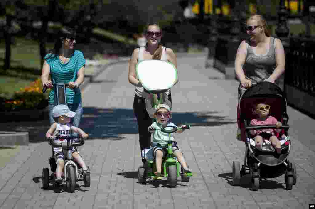 Local residents walk with their young children in a park, in Donetsk, May 21, 2014.