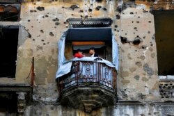 In this Nov. 12, 2018, photo, children stand on the balcony of their apartment building damaged during Lebanon's 1975-1990 civil war on a former Beirut frontline, Lebanon. (AP Photo/Hassan Ammar)