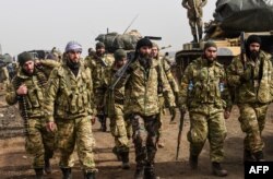 Syrian opposition fighters backed by Turkey walk in front of Turkish troops near the Syria border at Hassa, Hatay province on Jan. 22, 2018.