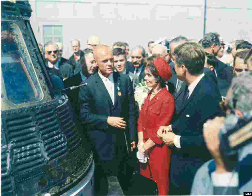 FILE - John Glenn, standing next to his Friendship 7 capsule in which he made his historic orbital flight, meets with President John F. Kennedy. Mrs. Glenn stands next to her husband.