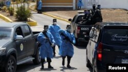 Miembros de la policía militar, con equipo de protección, bloquean la entrada de un cementerio antes del entierro de una víctima del coronavirus (COVID-19), en Tegucigalpa, Honduras.