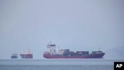 FILE- A cargo ship approaches the port of Piraeus as other ships are anchored, near Athens, Greece in this May 26, 2020, photo. 