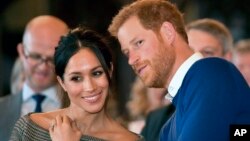 FILE - Britain's Prince Harry and Meghan Markle watch a dance performance in Cardiff, Wales, Jan. 18, 2018. 