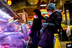 FILE - Customers wear face masks to protect against the spread of the coronavirus as they shop at the Reading Terminal Market in Philadelphia, Feb. 16, 2022.