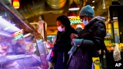 FILE - Customers wear face masks to protect against the spread of the coronavirus as they shop at the Reading Terminal Market in Philadelphia, Feb. 16, 2022. 