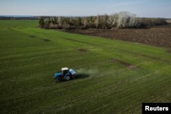 An aerial view shows a tractor spreading fertilizer on a wheat field near the village of Yakovlivka after it was hit by an aerial bombardment outside Kharkiv, as Russia's attack on Ukraine continues, April 5, 2022.