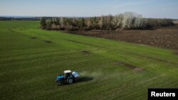 Pemandangan dari udara menunjukkan sebuah traktor menyebarkan pupuk di ladang gandum dekat desa Yakovlivka setelah dihantam oleh pemboman udara di luar Kharkiv, saat serangan Rusia ke Ukraina berlanjut, 5 April 2022. (Foto: Reuters