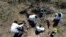 FILE - Forensic technicians excavate a field on a plot of land referred to as a cartel "extermination site" where burned human remains are buried, on the outskirts of Nuevo Laredo, Mexico, Feb. 8, 2022.