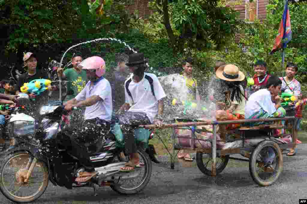 People use water guns to spray water at passing motorists along a street during Khmer New Year celebrations in Siem Reap province on April 14, 2022.