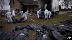 Добровольцы загружают тела мирных жителей, убитых в Буче, в грузовик для отправки в морг для расследования, 12 апреля 2022 года.