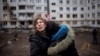 A woman reacts as she hugs another woman outside a heavily damaged apartment block in Kharkiv following an artillery attack amid Russia's invasion of Ukraine, April 13, 2022.