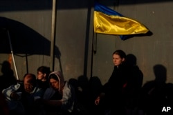 Ukrainian refugees wait near the U.S. border Monday, April 4, 2022, in Tijuana, Mexico. (AP Photo/Gregory Bull)