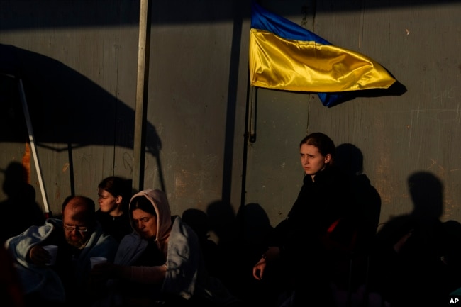 Ukrainian refugees wait near the U.S. border Monday, April 4, 2022, in Tijuana, Mexico. (AP Photo/Gregory Bull)