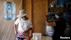 A woman is attended to in a soup kitchen in Pamplona Alta, a low-income neighborhood, in Lima, Peru April 11, 2022. (REUTERS/Daniel Becerril)